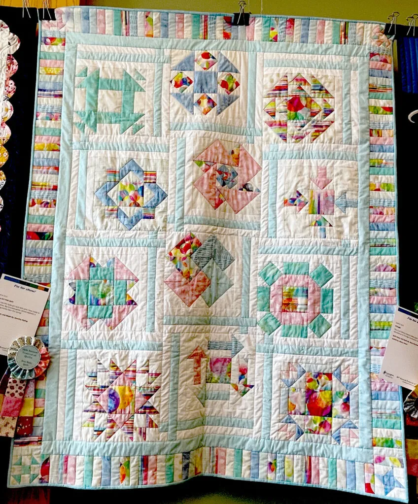 Baby quilt featured blocks of pastel colors of blues, greens and pinks