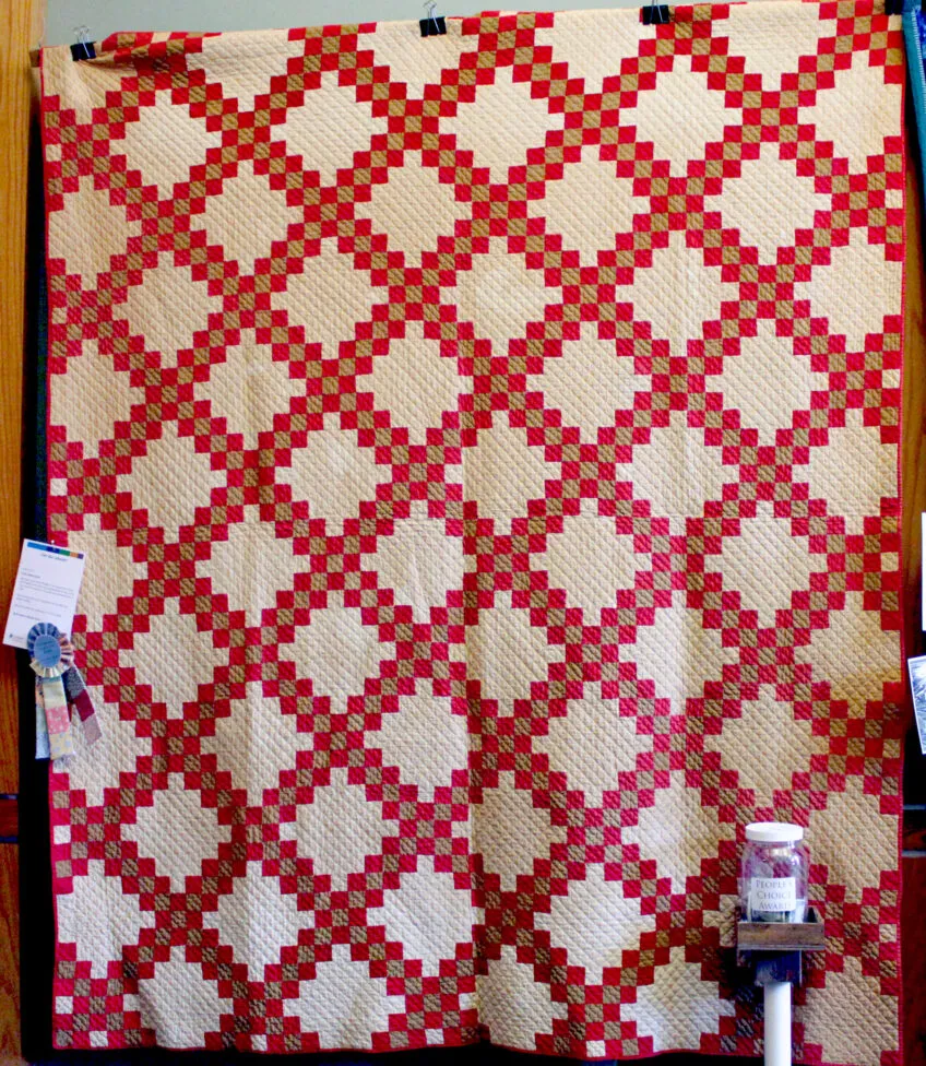 Classic quilt using red and tan diamond shaped blocks with cream colored interior.