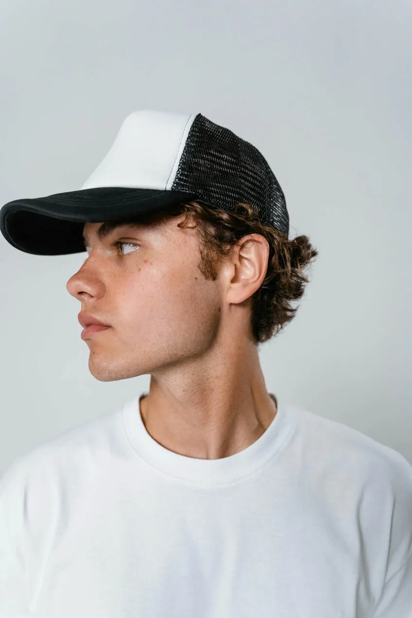 Teenage boy in white t-shirt wearing a white and black ball cap.