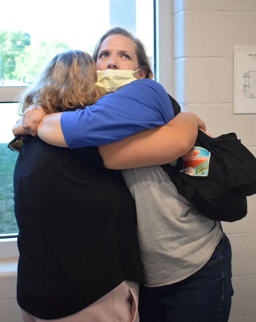 teacher assistant hugging a student