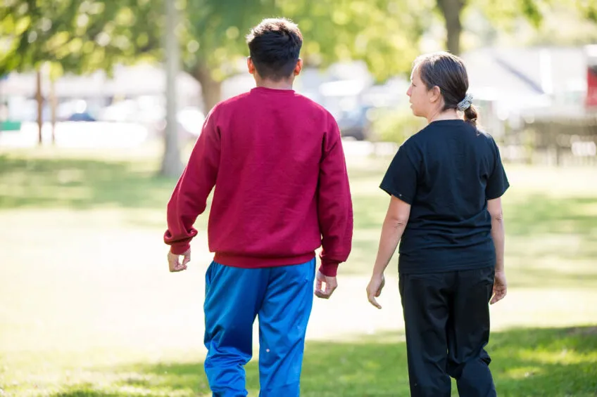 A female youth care professional talking and walking on campus with a youth in care.