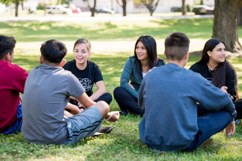 Youth care professionals sitting in a circle with youth and smiling