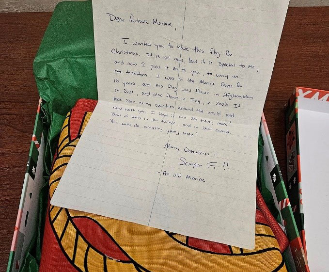 Picture of a handwritten note on top of a gift box with a folded Marine Corps. flag inside