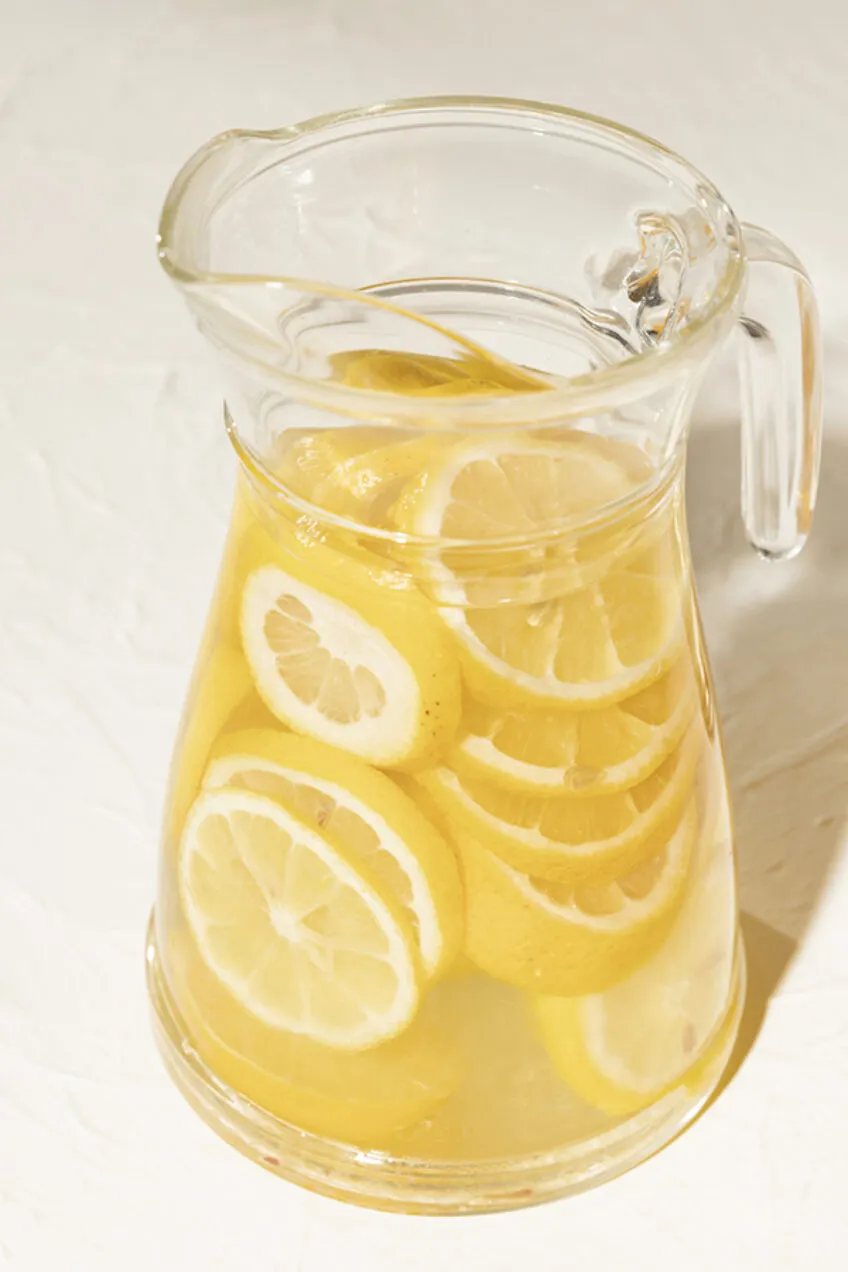 clear glass pitcher of lemonade filled with sliced lemons